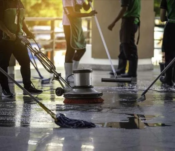 People using floor-care equipment and mops in an indoor space.